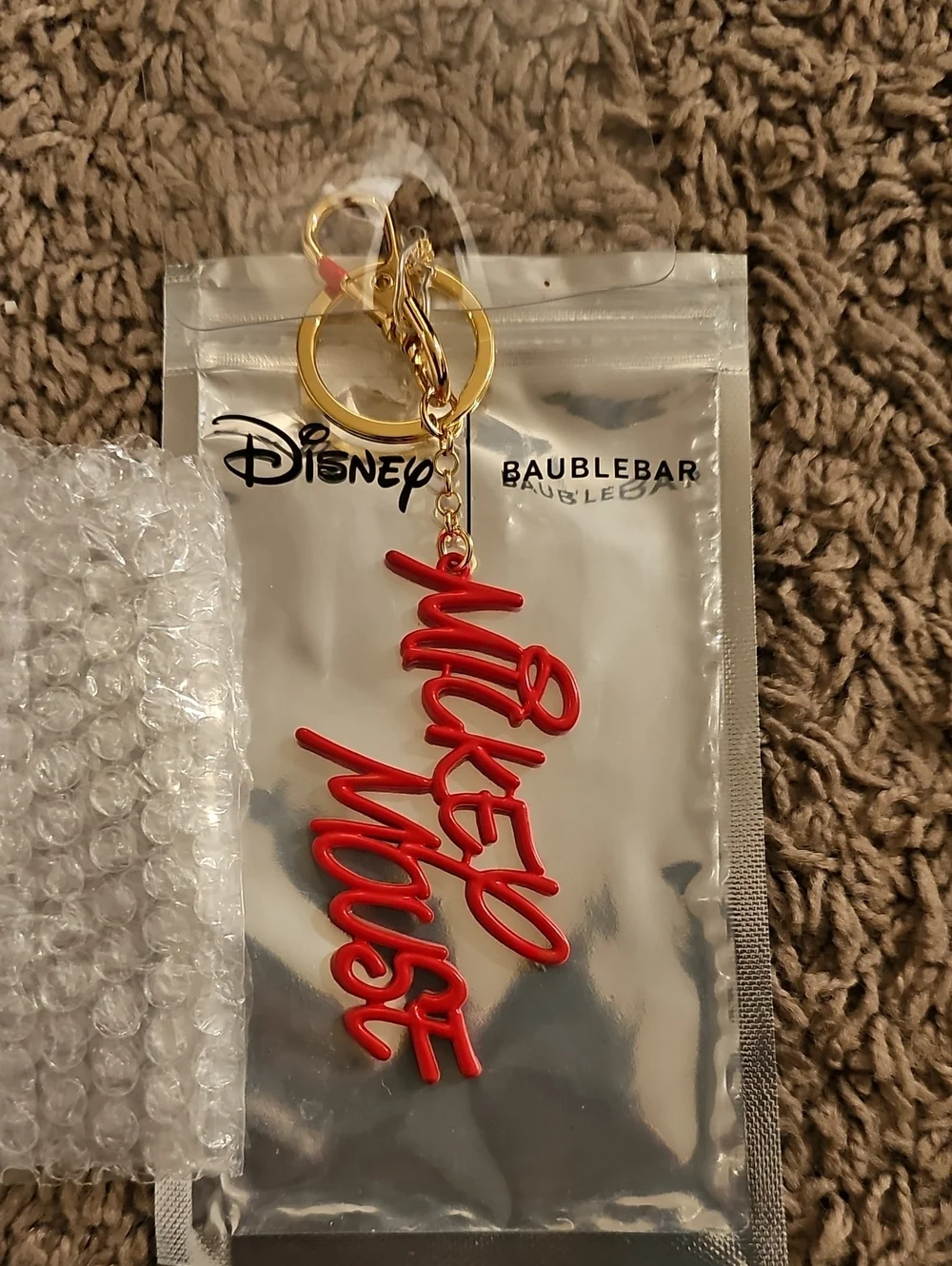 Disney x BaubleBar keychain/ornament (text 'Mickey Mouse'). cursive red text.